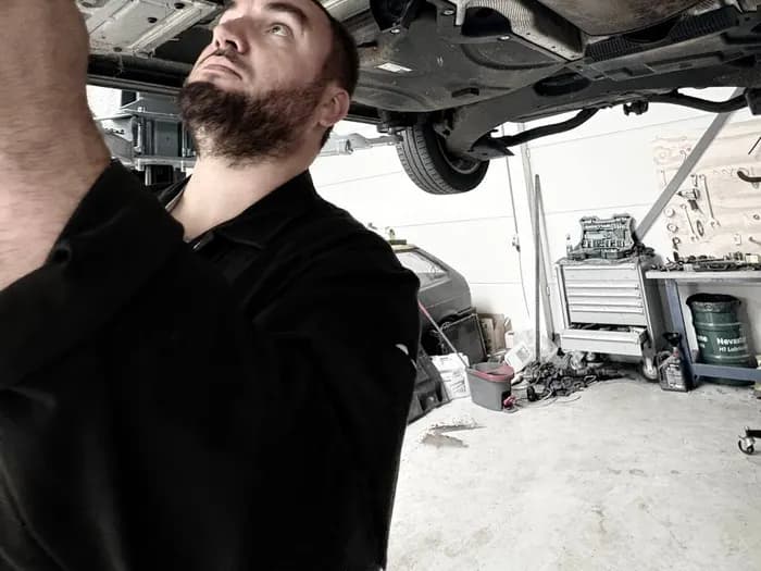 Monteur werkt aan de onderkant van een auto op de hefbrug