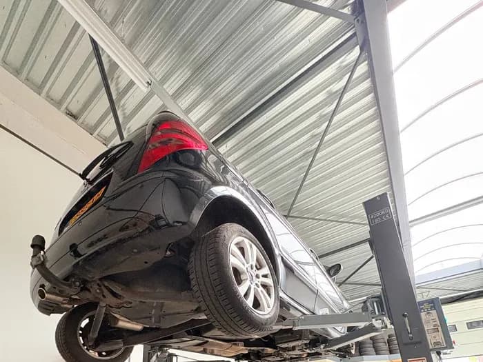 Auto hoog op de hefbrug in de werkplaats van Prima Auto's