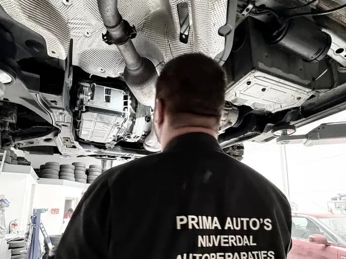 Prima Auto's werkkleding met logo tijdens werk onder een auto