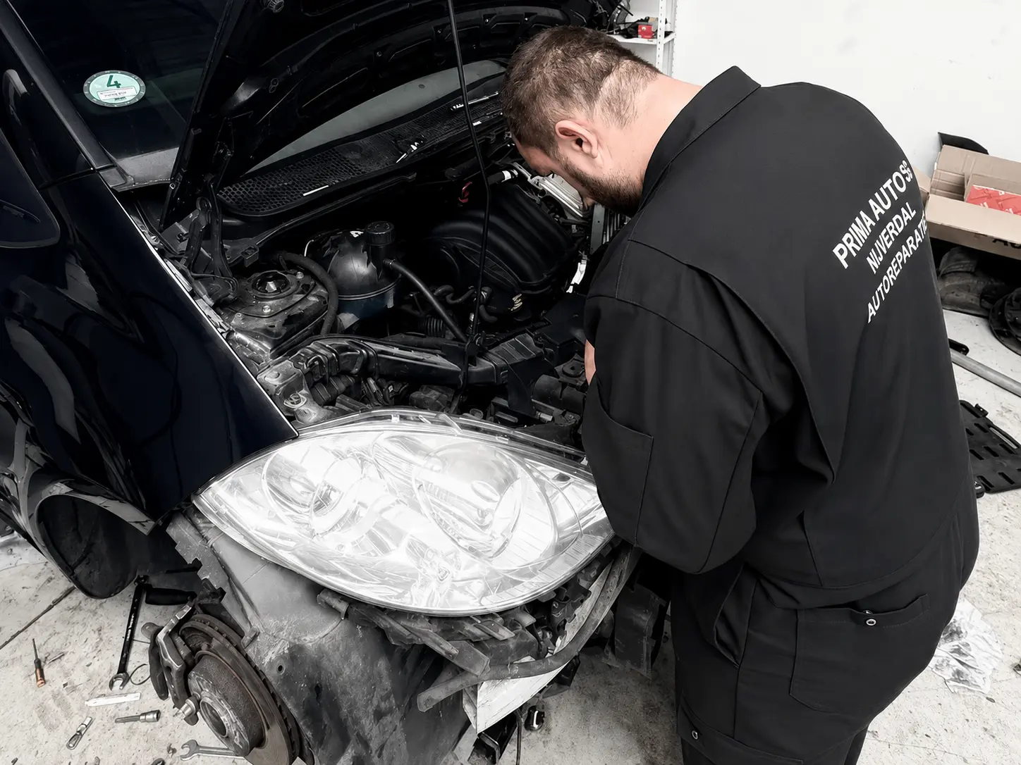 Monteur werkt aan de motor en de voorkant van een auto