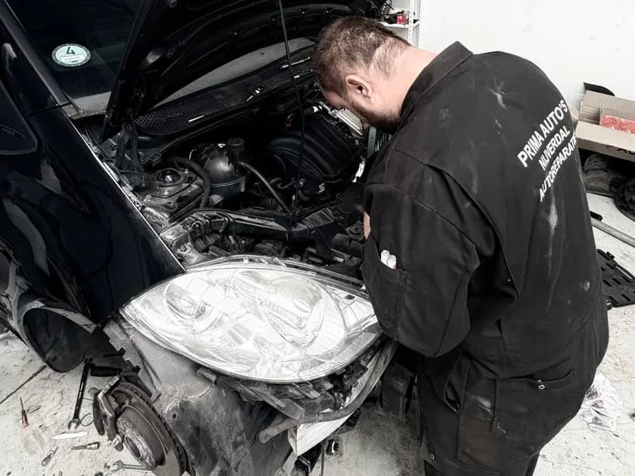 Monteur werkt aan de motor en de voorkant van een auto
